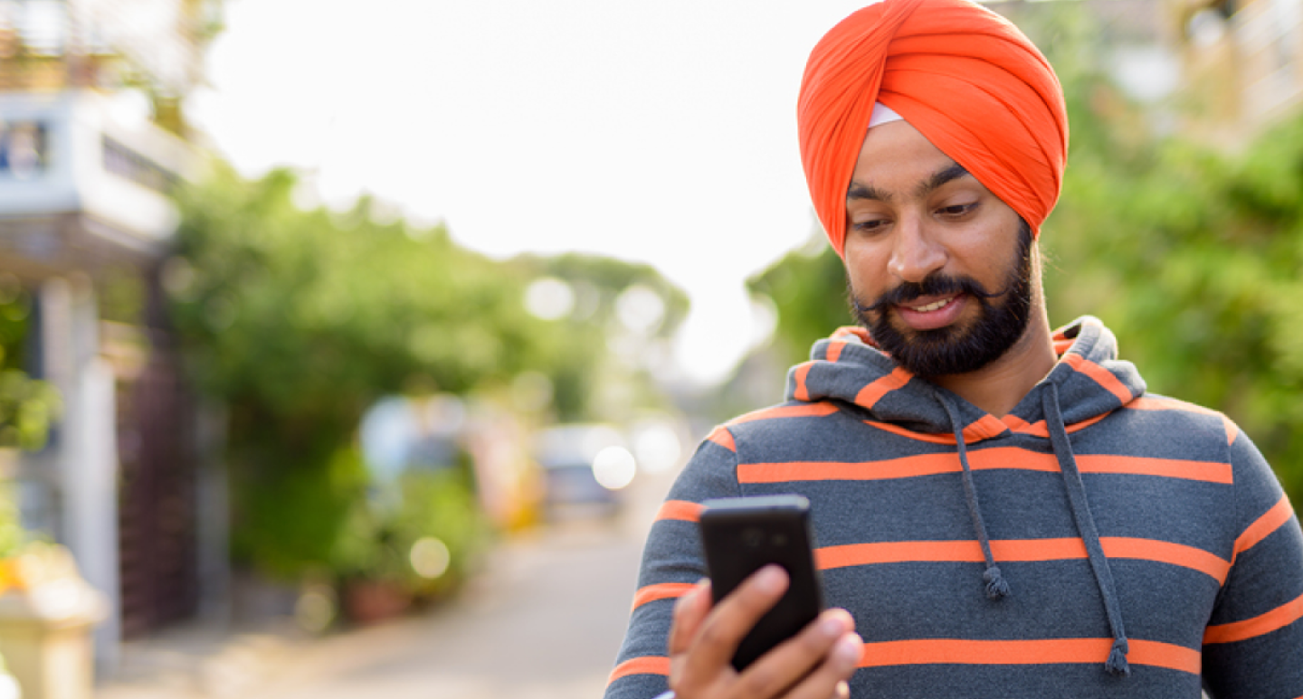 man in orange holding phone 1440 x 773.png